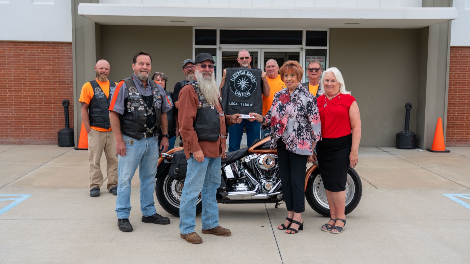 EWRC1 members in vests presenting a charity donation check outside the IBEW Local 1 union hall.